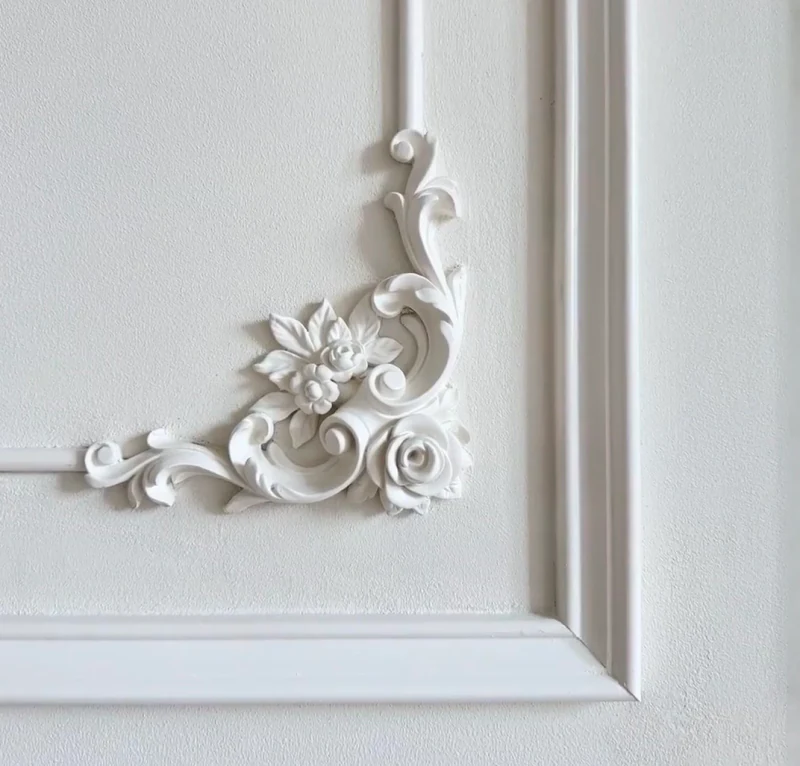 White floral scrollwork corner ornament within framed wall moulding