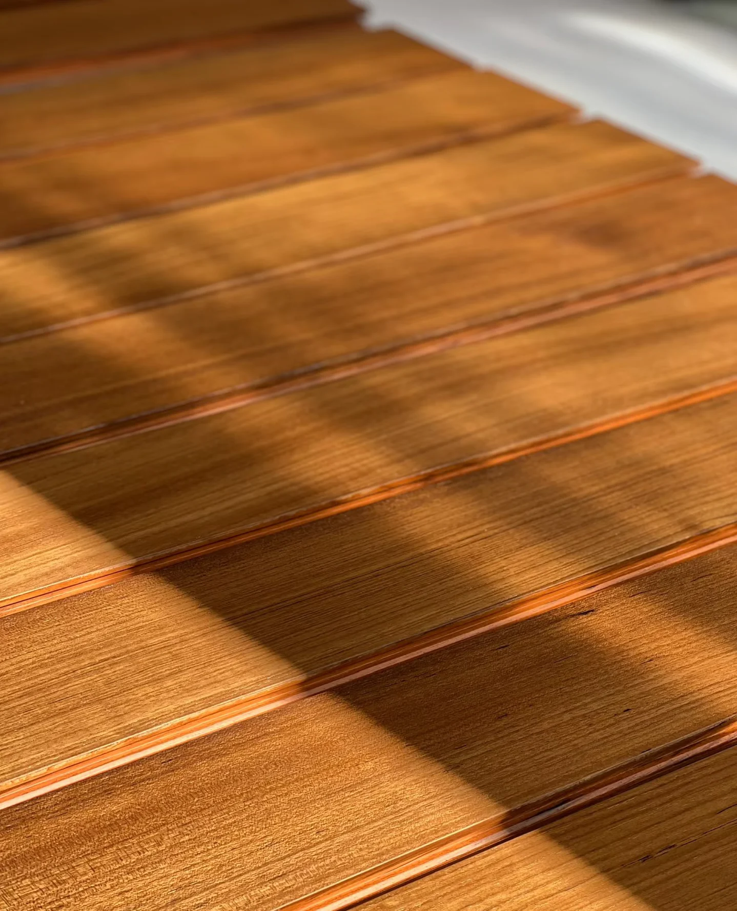 Warm-toned wood flooring boards with visible grain under angled sunlight