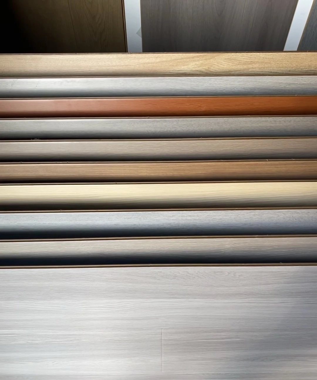 Overlapping flooring samples showing grey, natural and reddish wood-tone finishes
