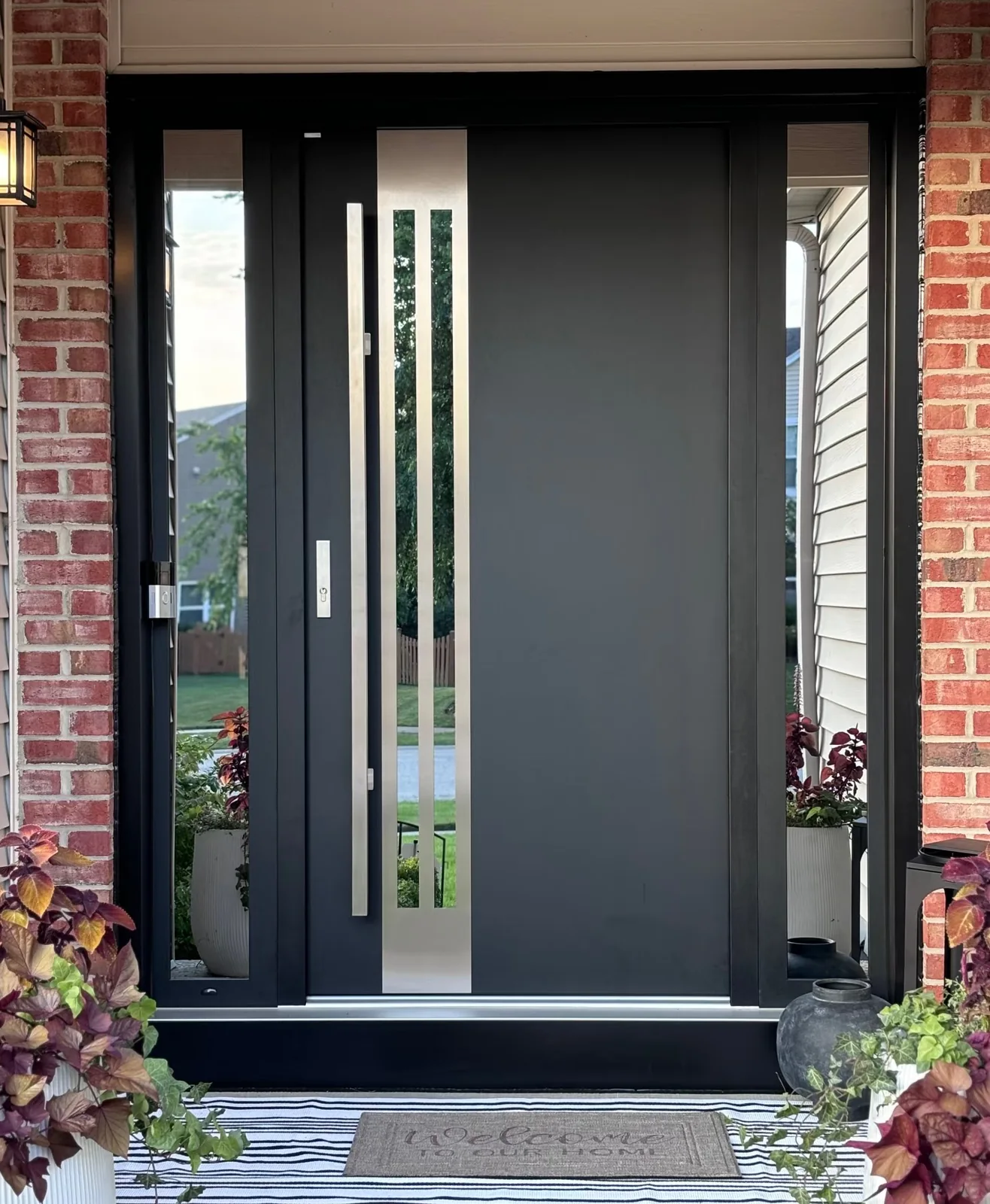 Dark custom entry door with vertical glazing in a residential facade