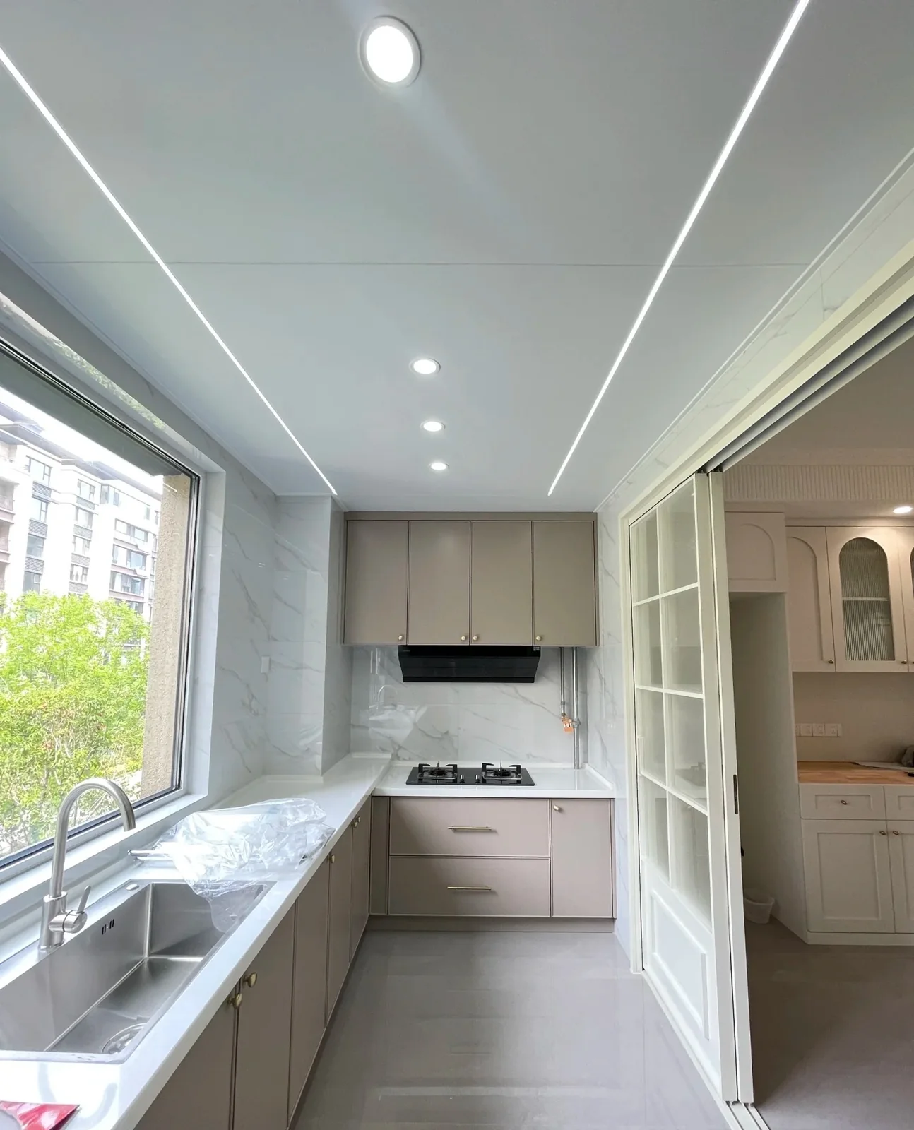 Light aluminum kitchen cabinets arranged in a narrow room