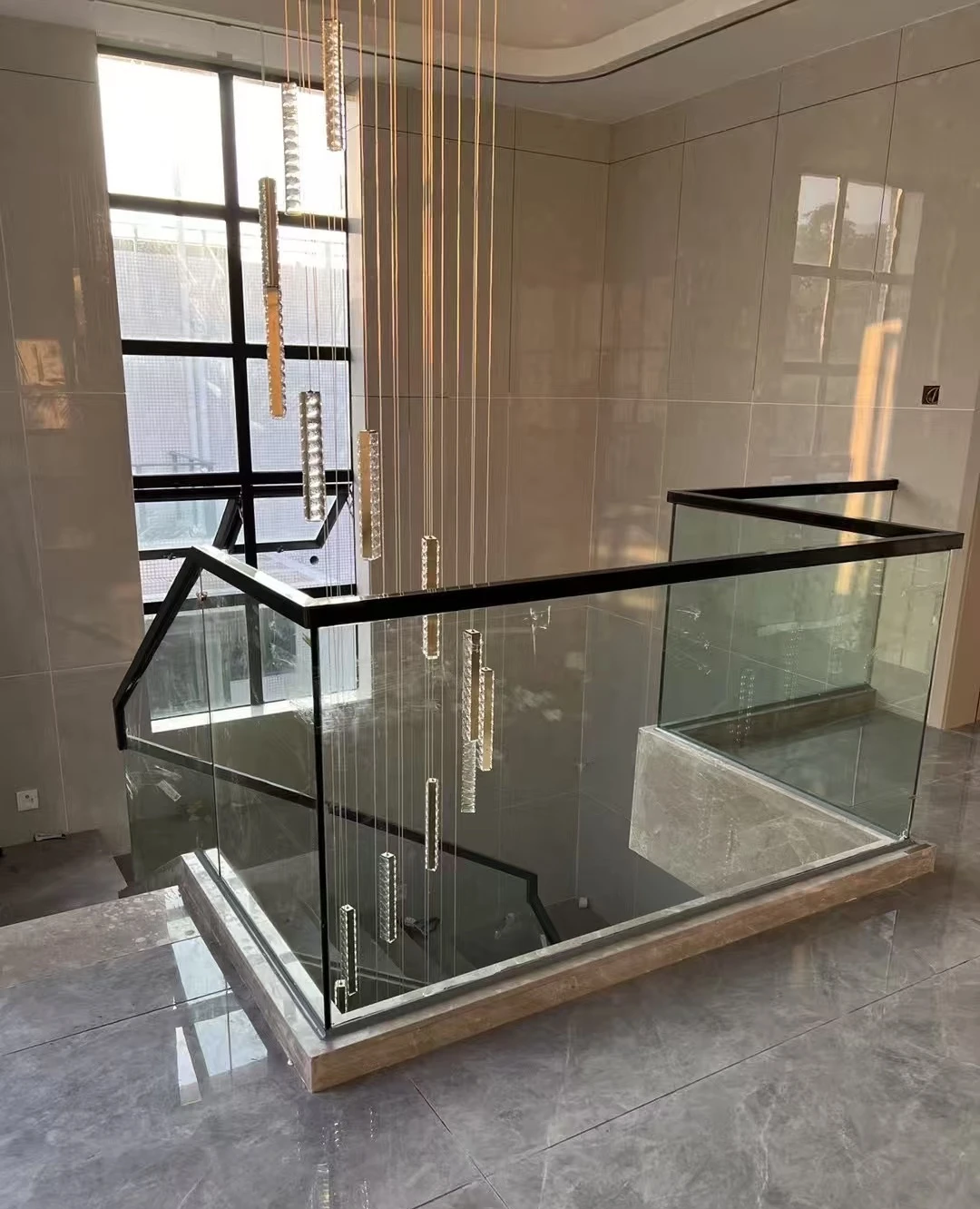 Clear glass landing balustrade with a black top handrail around a stone-look stair opening