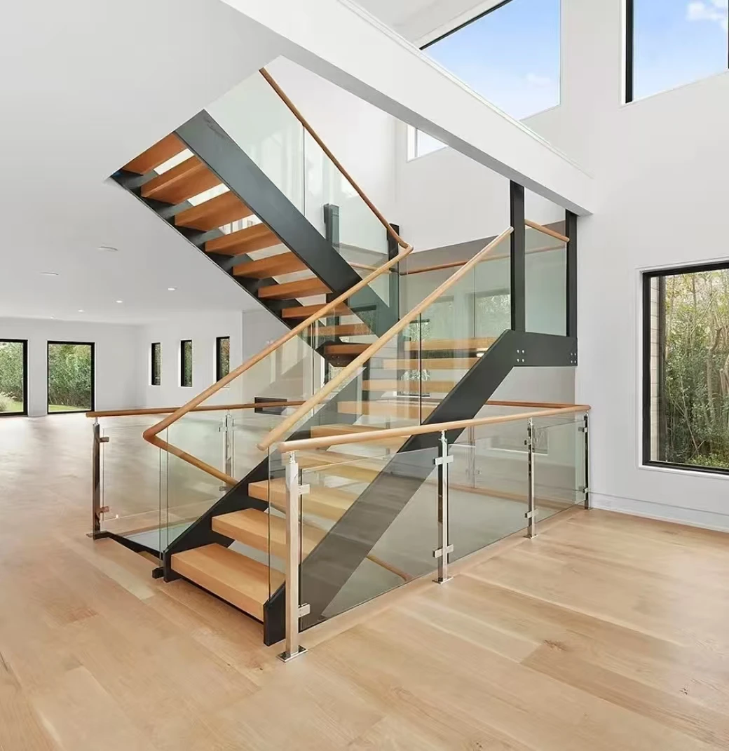 Open-riser wood staircase with dark steel stringers, clear glass panels and wood handrails