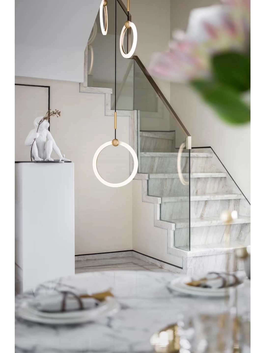 Glass stair balustrade following the stepped edge of a pale stone-look staircase with a slim top rail