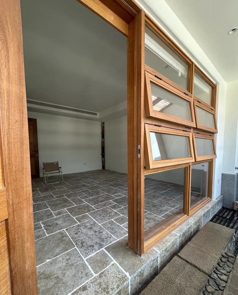 Wood-tone folding window panels beside a matching glazed doorway and a dark stone floor