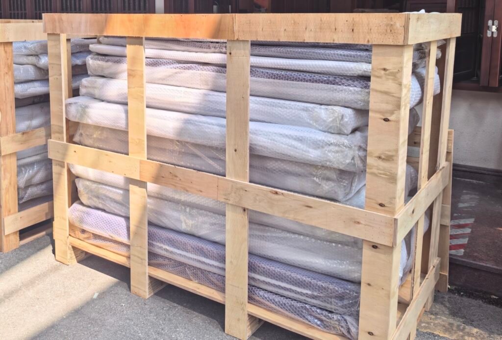 Bubble-wrapped long components stacked inside an open wooden frame