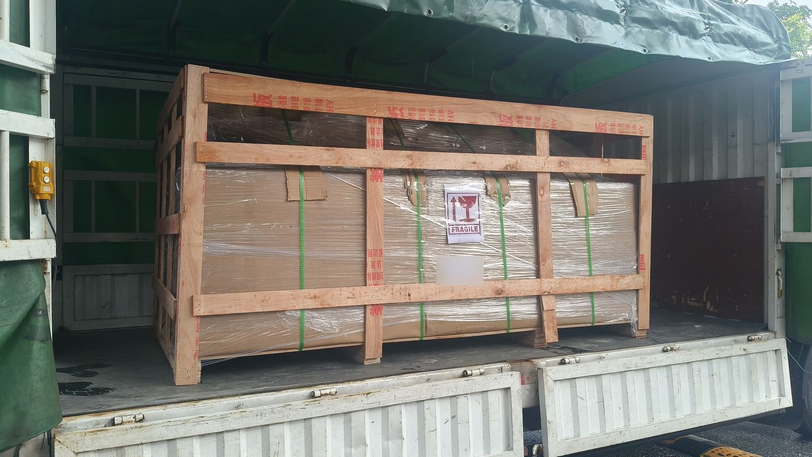 Wooden crate with a FRAGILE label loaded on the bed of a covered truck