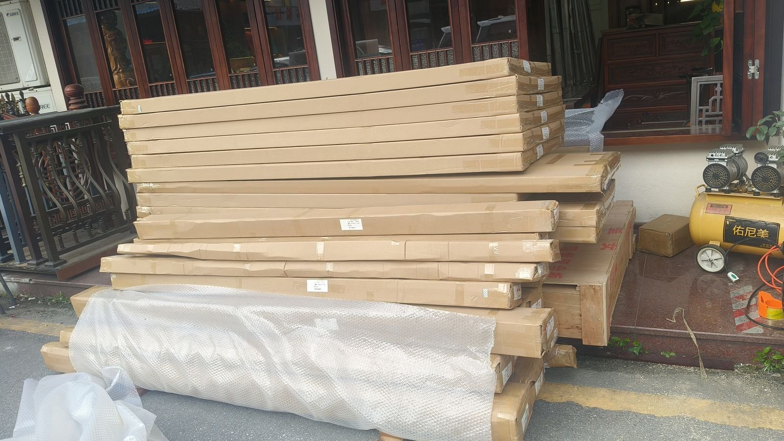 Flat cartons of door and window components stacked on a wooden base, with a bubble-wrapped item in front
