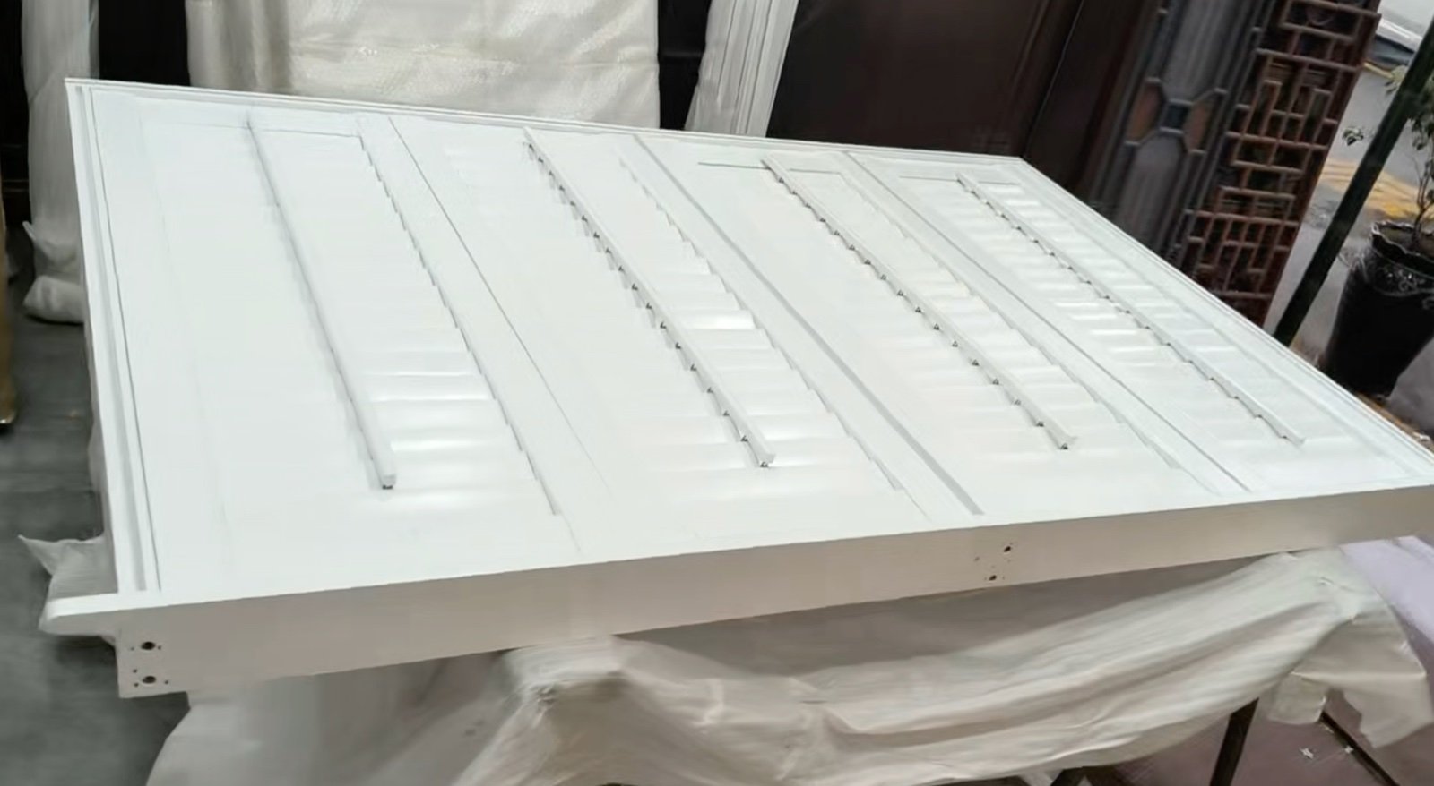 White solid wood plantation shutter panels with closed louvers and visible front tilt rods